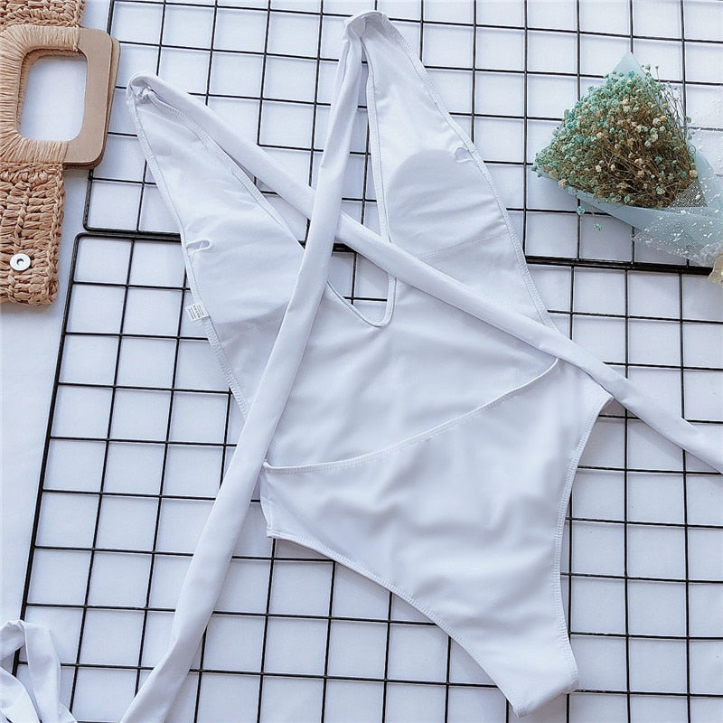 White one-piece swimsuit laid flat with crossed straps and wrap-tie waist