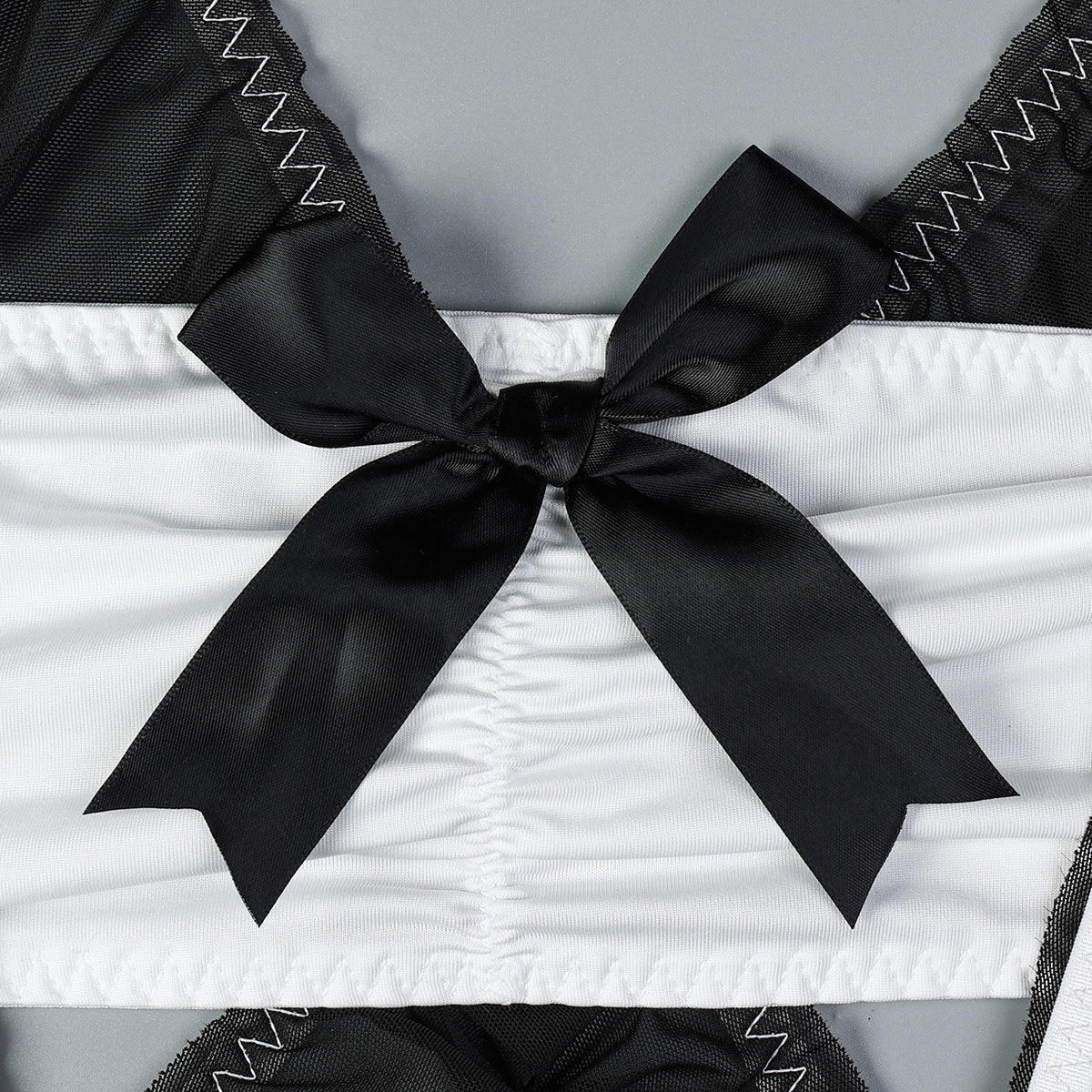 Black lingerie bodice with large satin bow and zigzag-edged mesh trim.