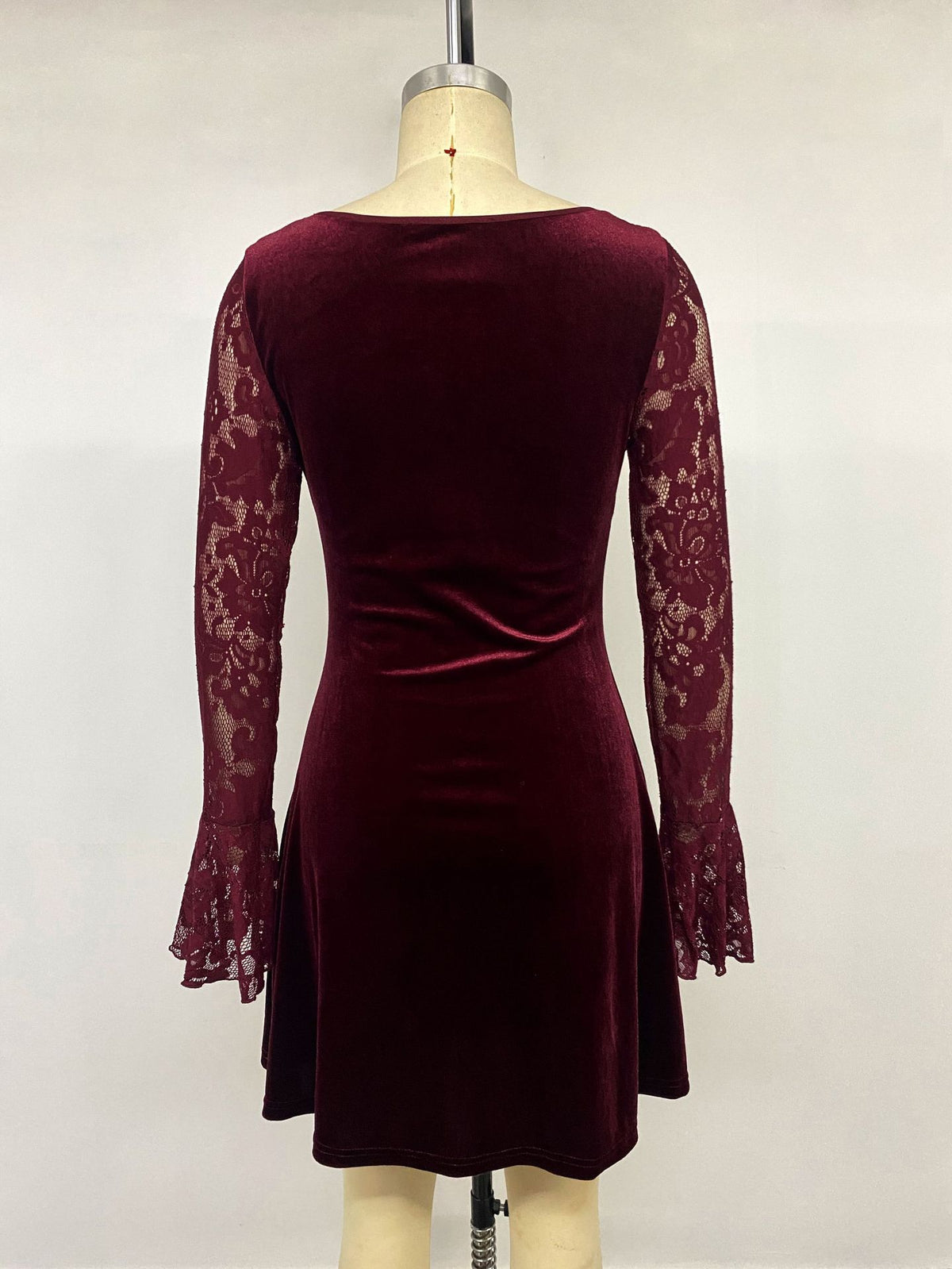 Burgundy velvet mini dress on mannequin with lace sleeves and open-back style