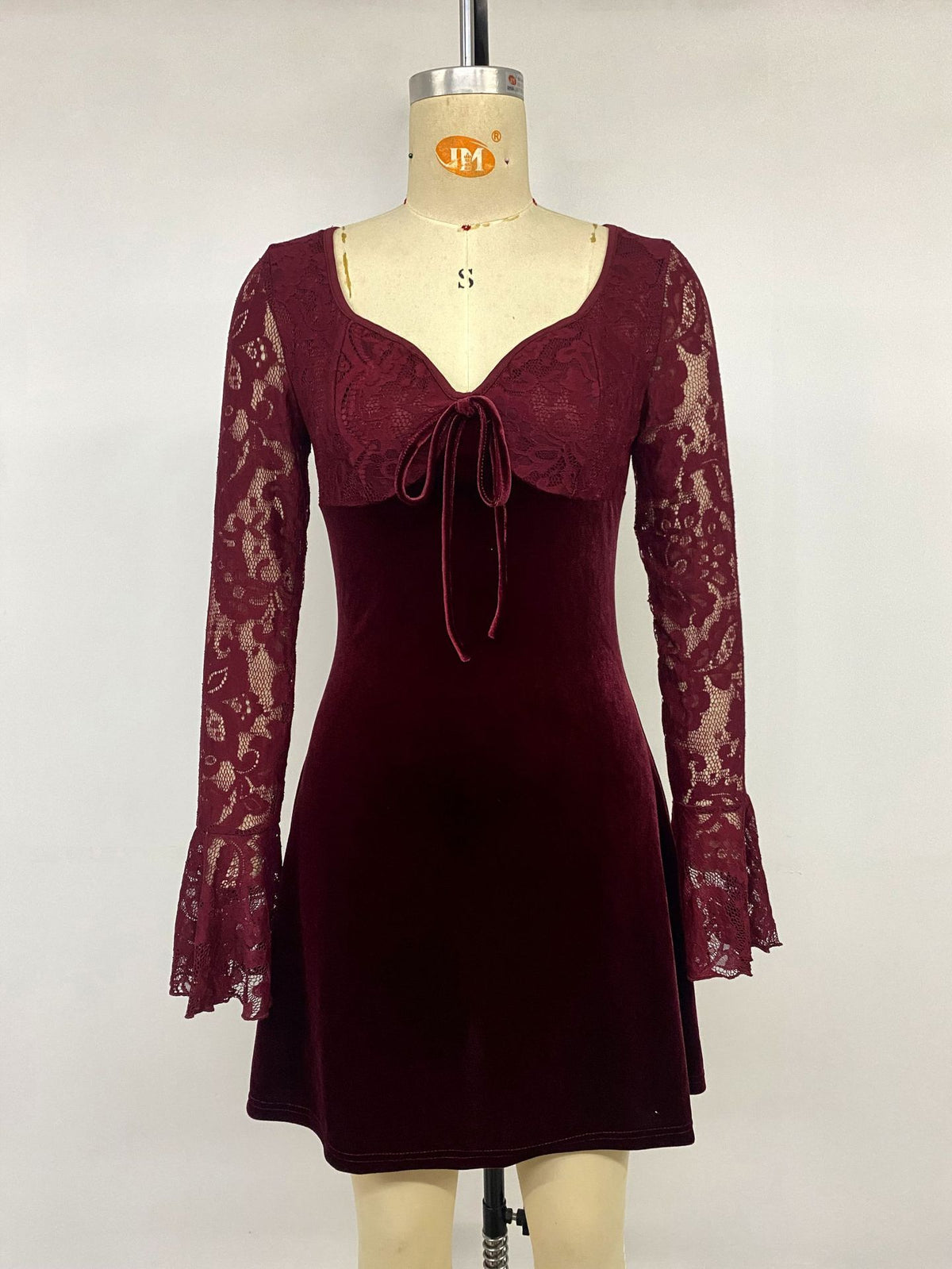 Burgundy velvet mini dress on mannequin with lace sleeves and front bow