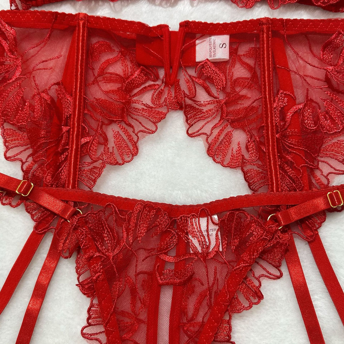 Red sheer floral lace lingerie garter belt with hook-and-eye closure and ribbon straps.
