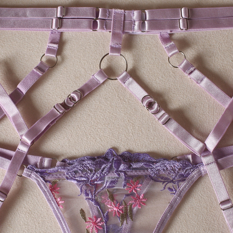 Lilac garter belt with crisscross straps and metal adjusters beneath a lace thong