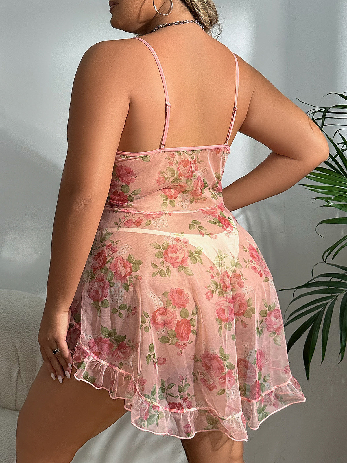 Back view of pink floral sheer babydoll with open-back straps and ruffled hem