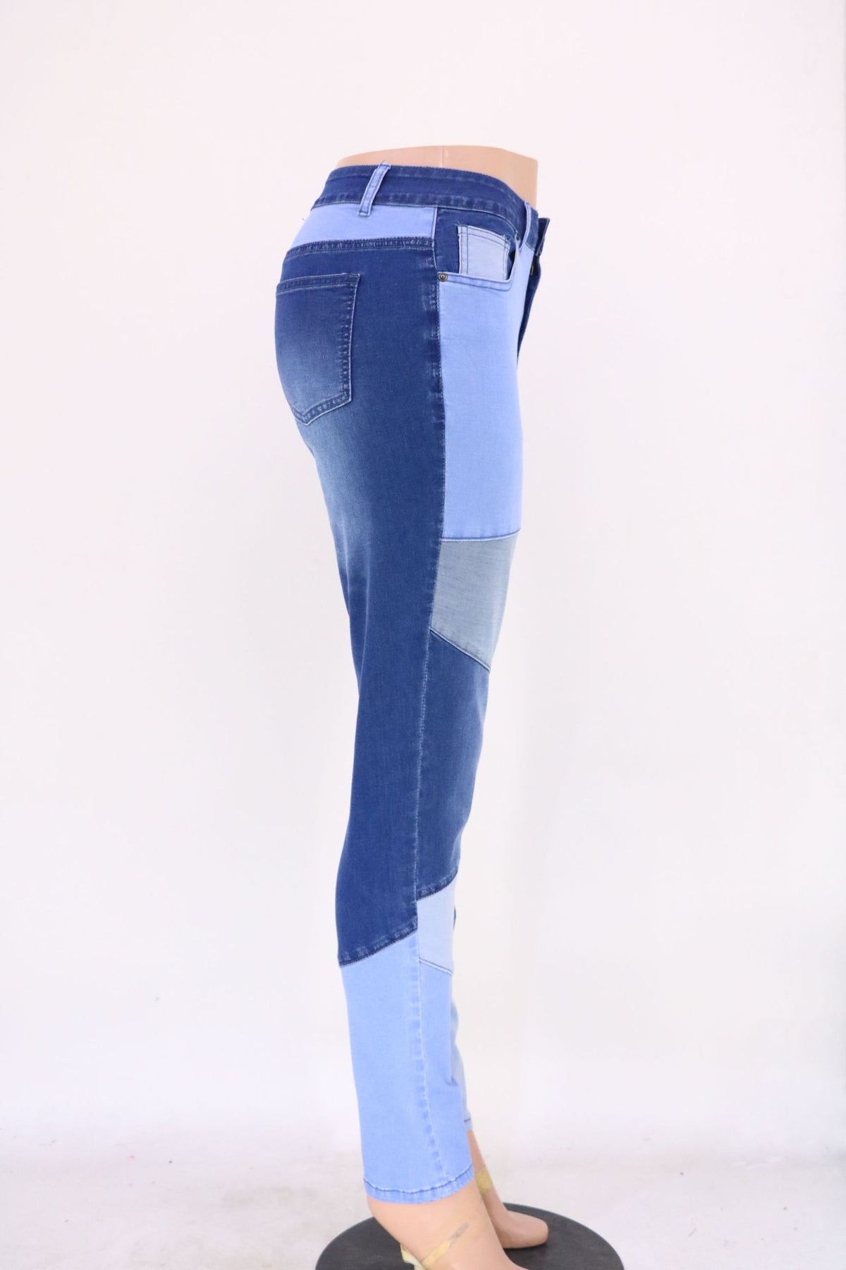 High-waist patchwork jeans with angled panel seams and slim leg, blue with light blue sections.