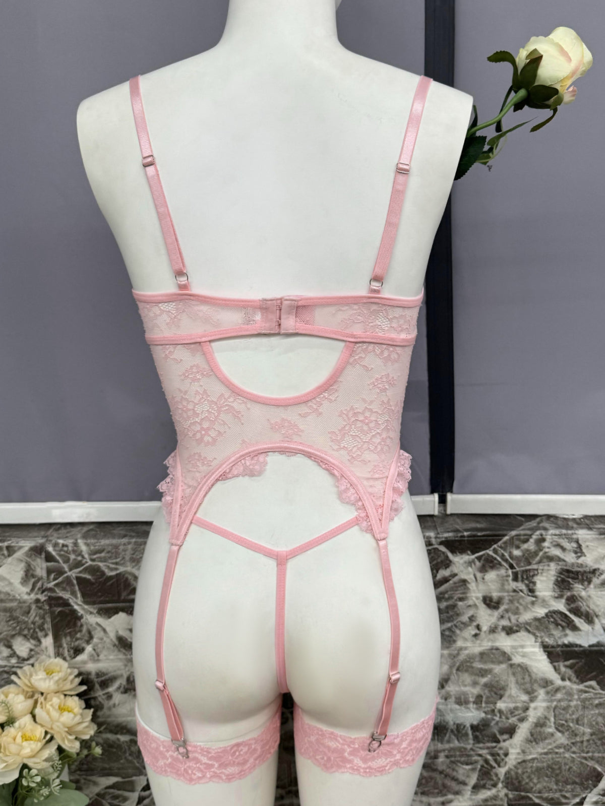 Pink lace bustier set back view on mannequin with cross-strap garters