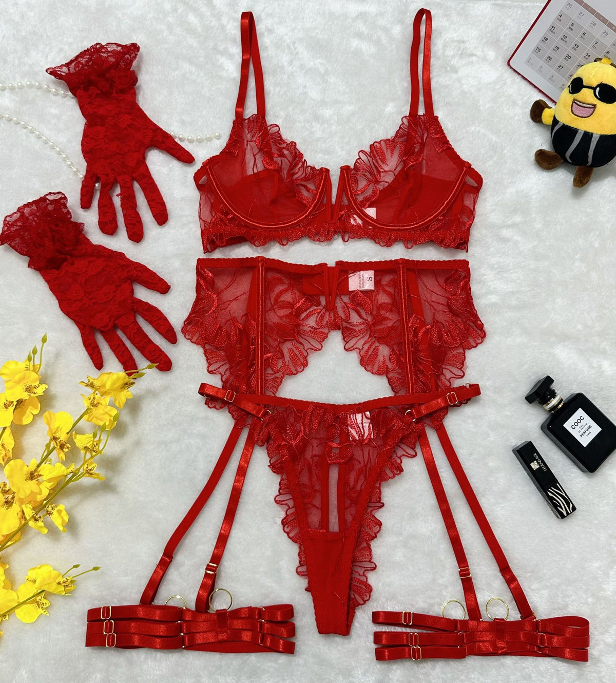 Red lace lingerie set flat lay with bra, garter belt, high-waist bottoms, and cuffs