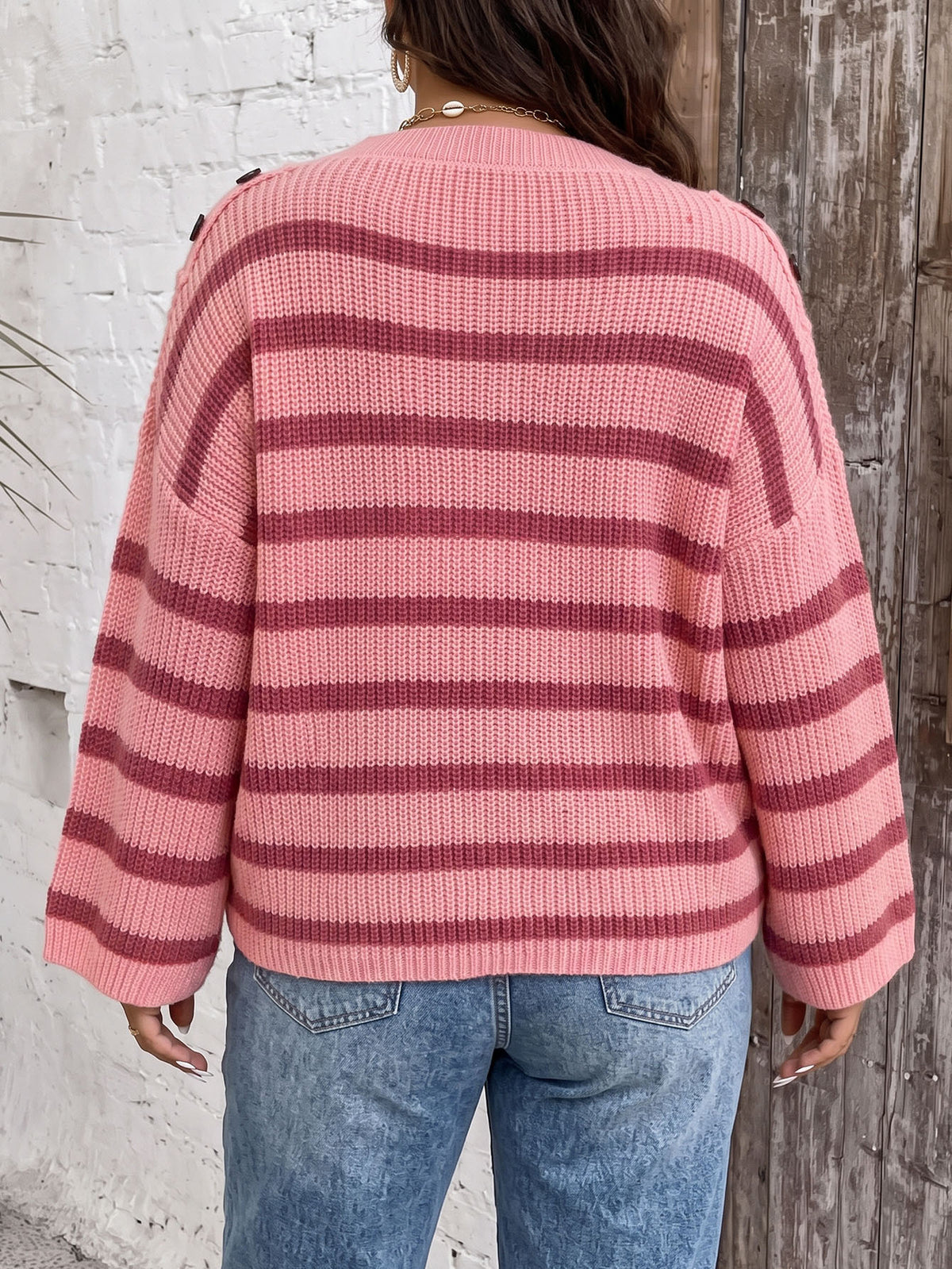 Back view of pink striped knit pullover sweater with wide bell sleeves