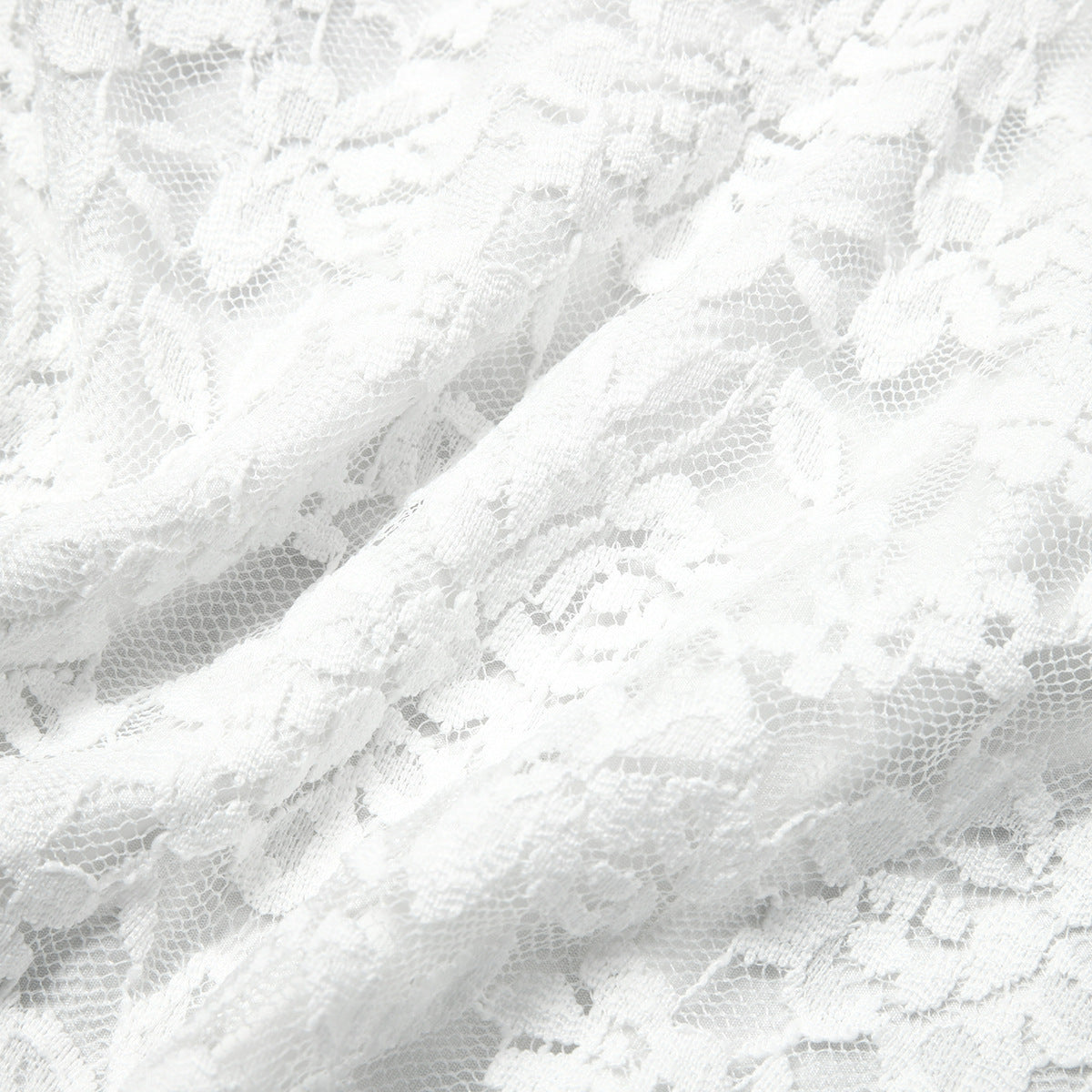 White lace bodysuit fabric close-up with intricate scalloped pattern