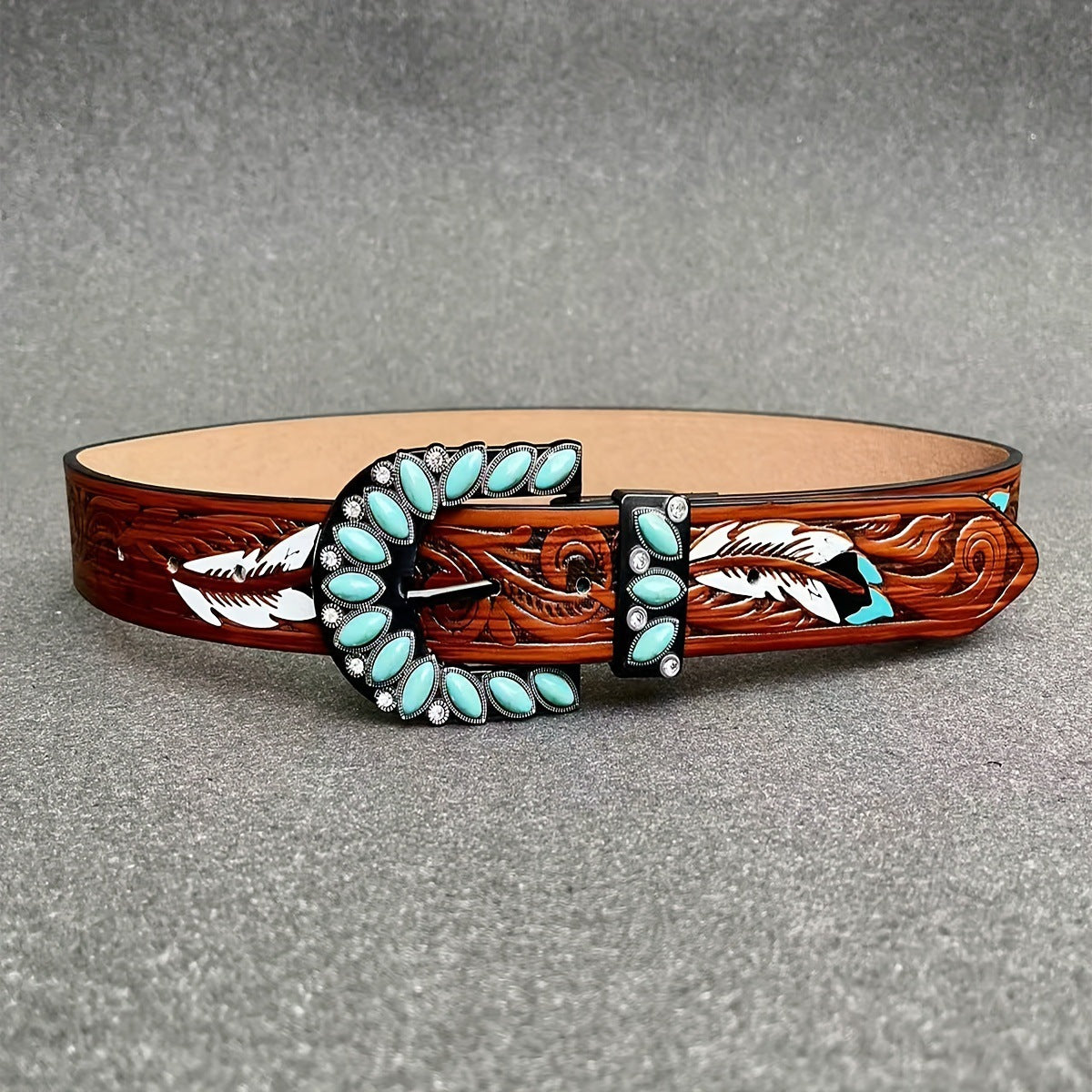 Western feather belt flat lay: brown tooled leather with turquoise stone oval border and buckle