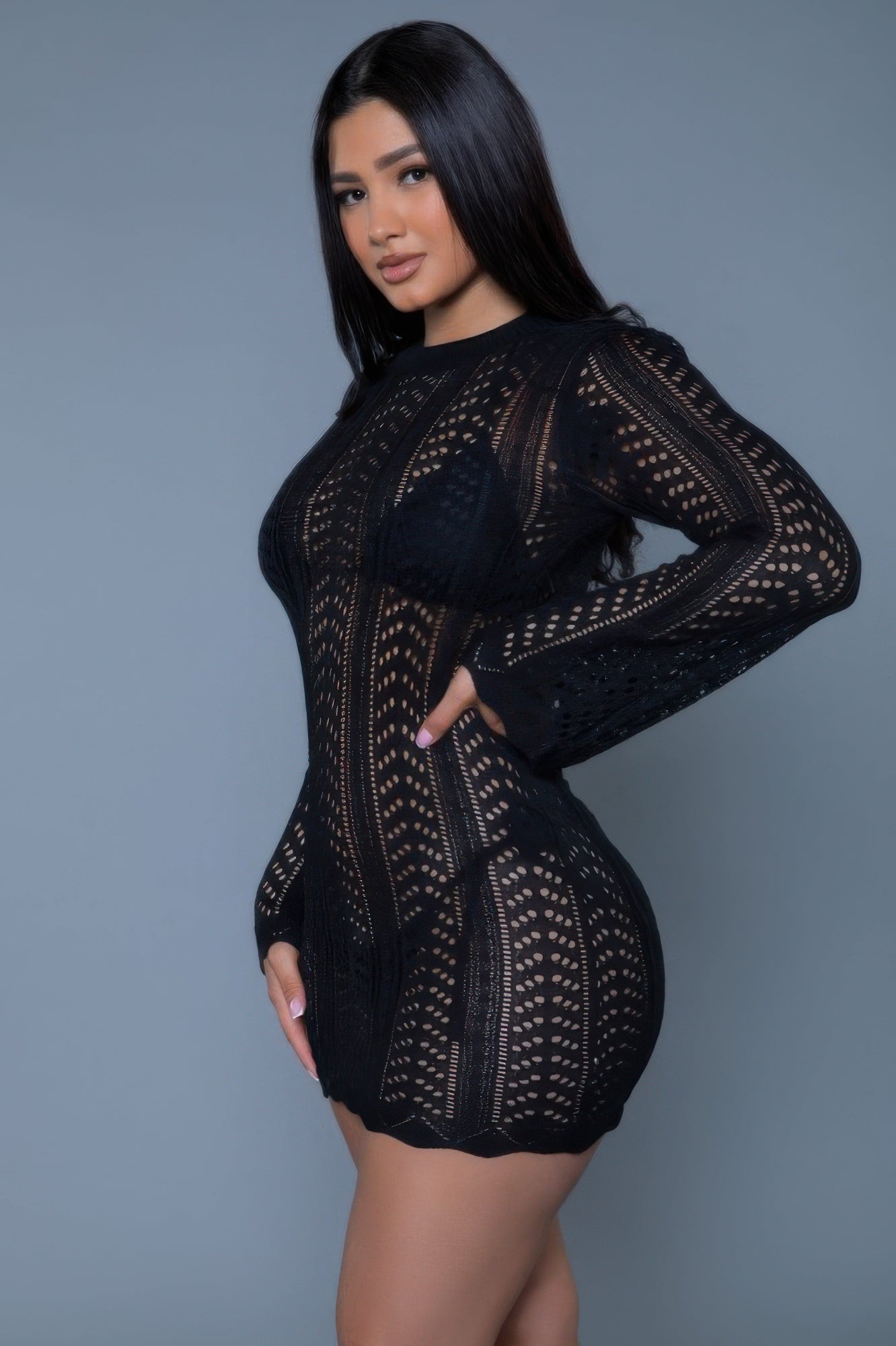 Model in CCWHOLESALECLOTHING black crochet mini dress long sleeve fitted sheer pattern