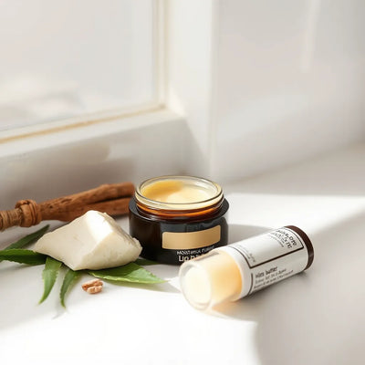 Moisturizing lip balm container and balm stick on a clean counter with natural ingredients nearby