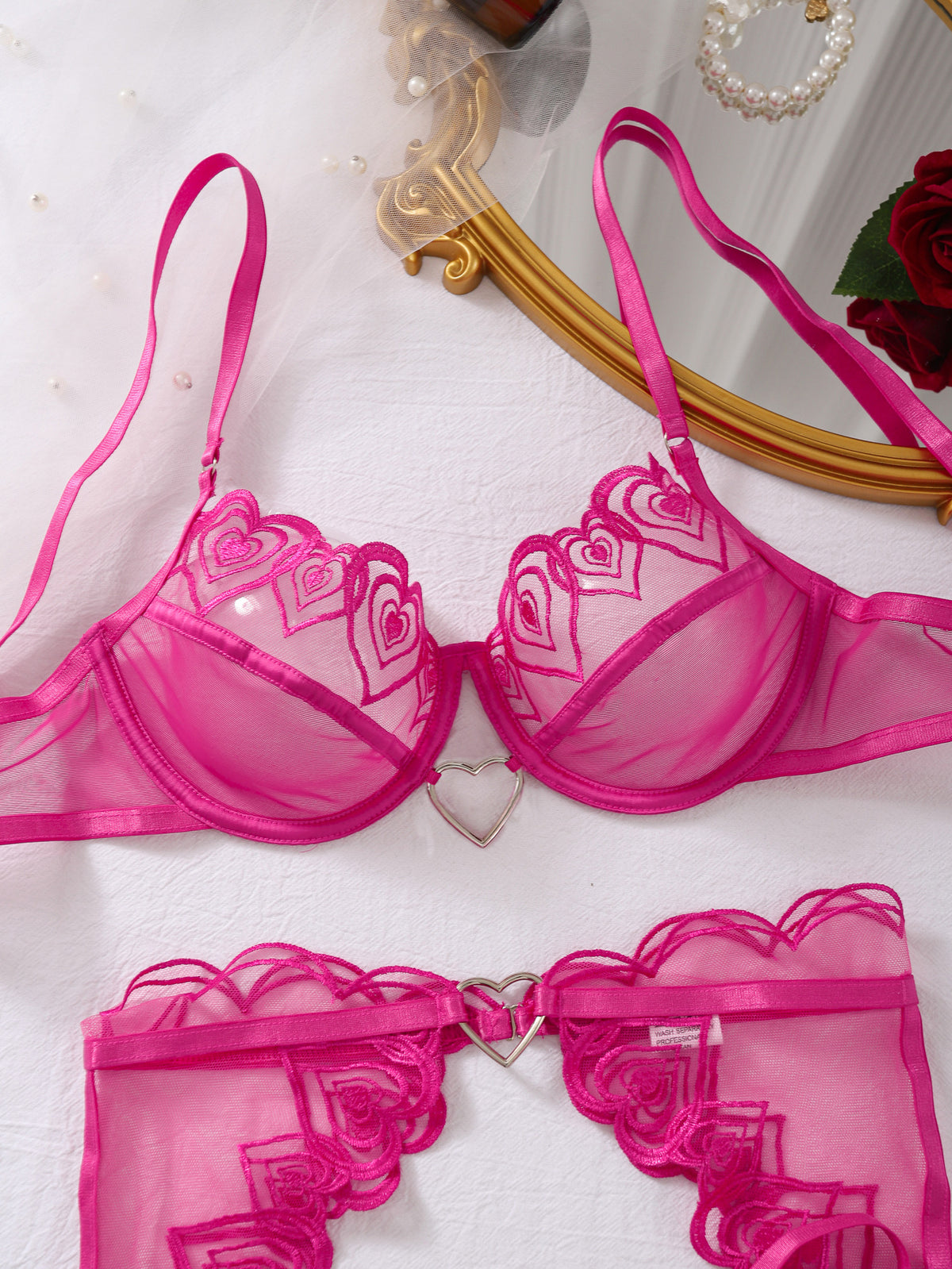 Rose red heart-embroidered sheer mesh bra and panty lingerie set laid flat