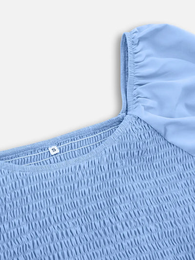 Close-up of light blue smocked neckline and puff sleeve seam