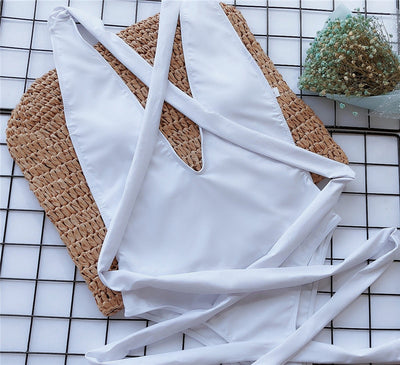 White one-piece swimsuit flat lay with crossed straps and wrap-tie waist