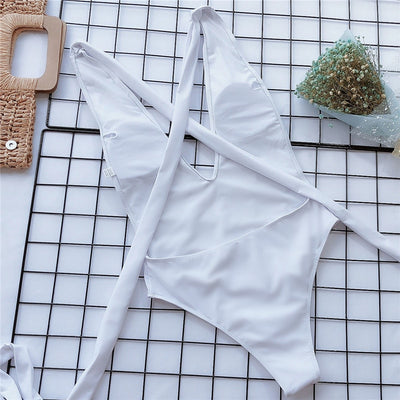 White one-piece swimsuit laid flat with crossed straps and wrap-tie waist