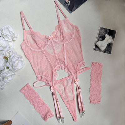 Pink lace bustier set flat lay with garter straps, thong, and lace cuffs