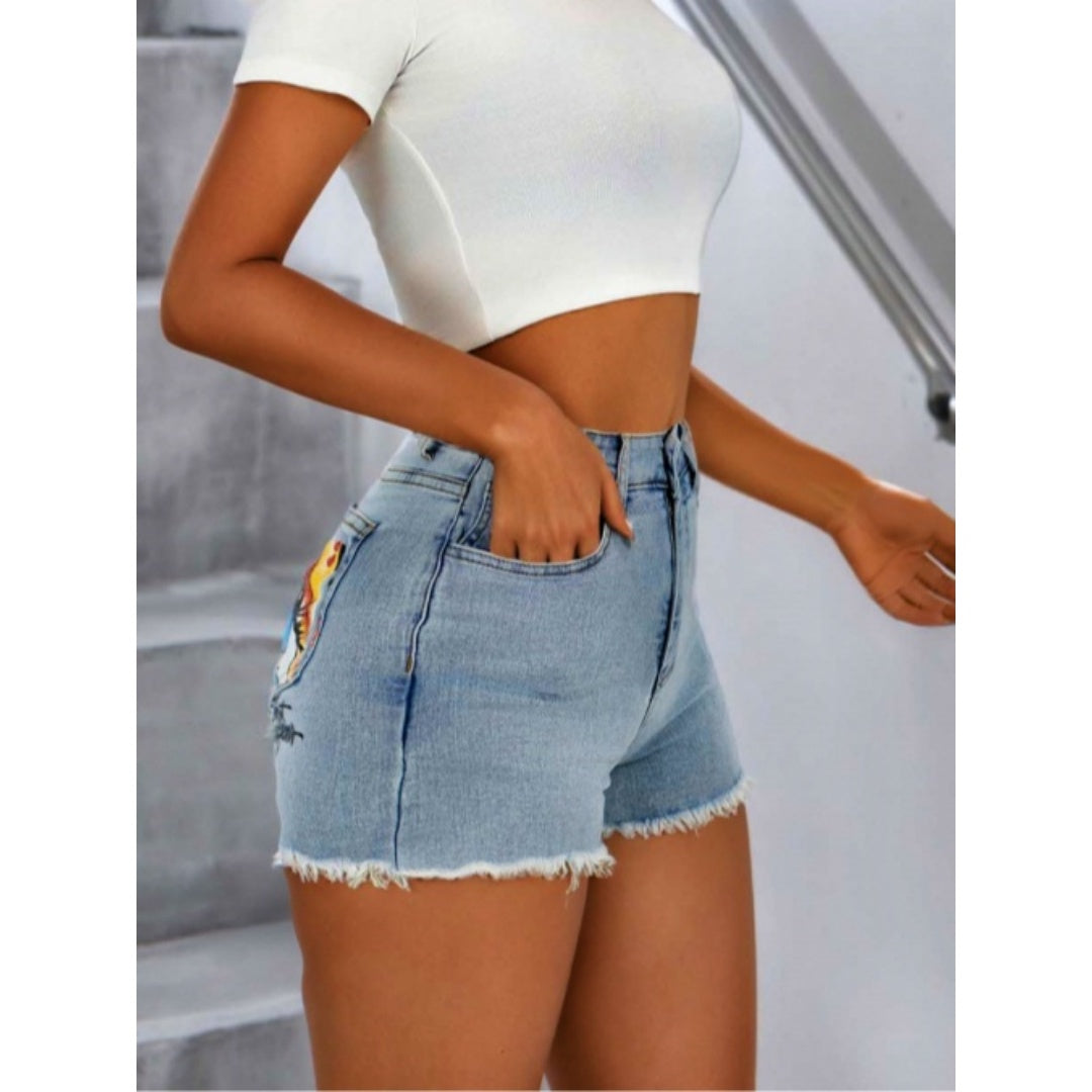 Light blue denim shorts with frayed hem and eye-print pocket, side view