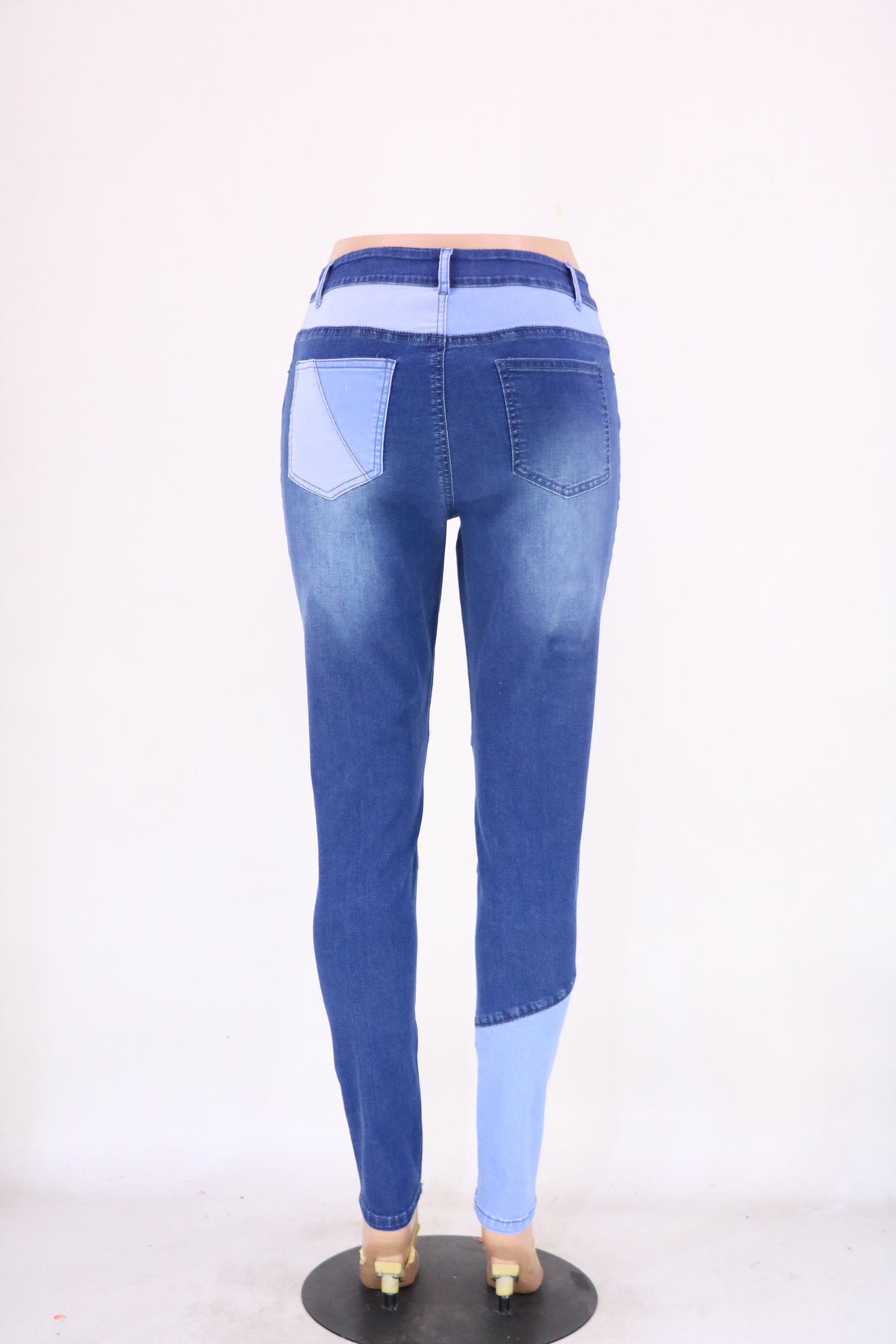 High-waist patchwork jeans with angled panel seams and slim leg, blue with light blue patches.
