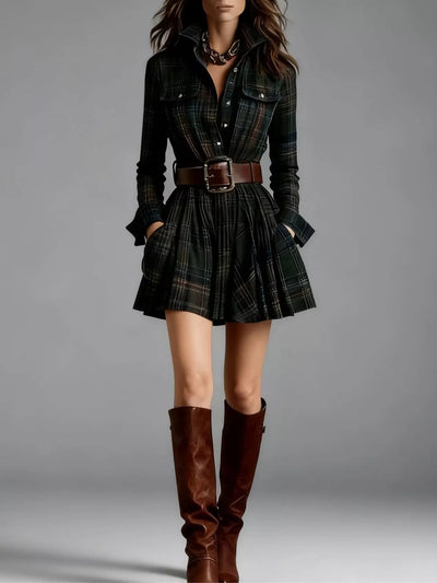 Woman wearing a plaid dress with a belt and brown knee-high boots on a gray background