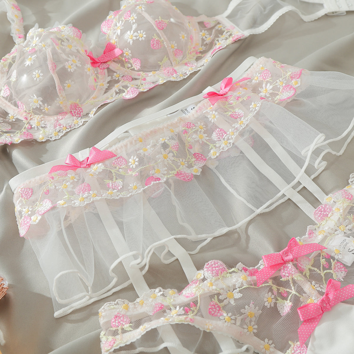 Floral embroidered lingerie set flat lay with ruffled bra, garters, and matching panties