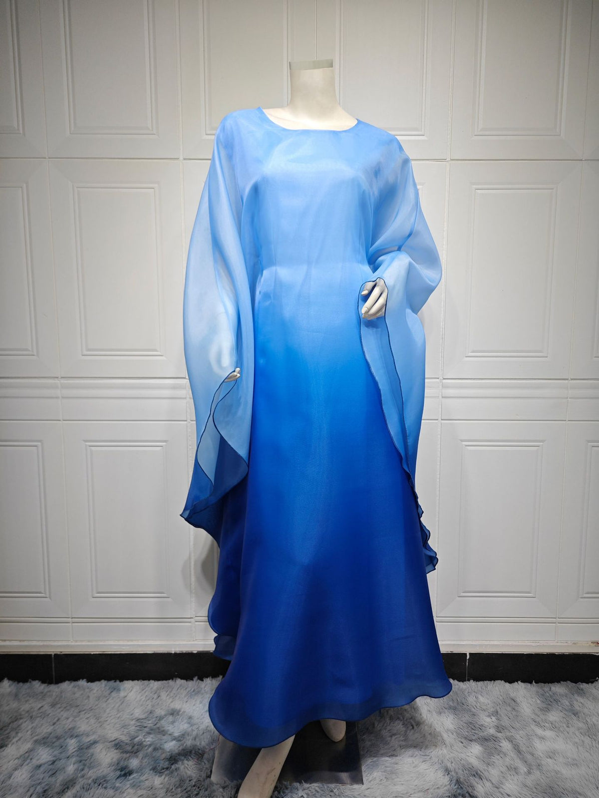 Ombre satin maxi dress with sheer batwing sleeves in blue, draped side overlay.