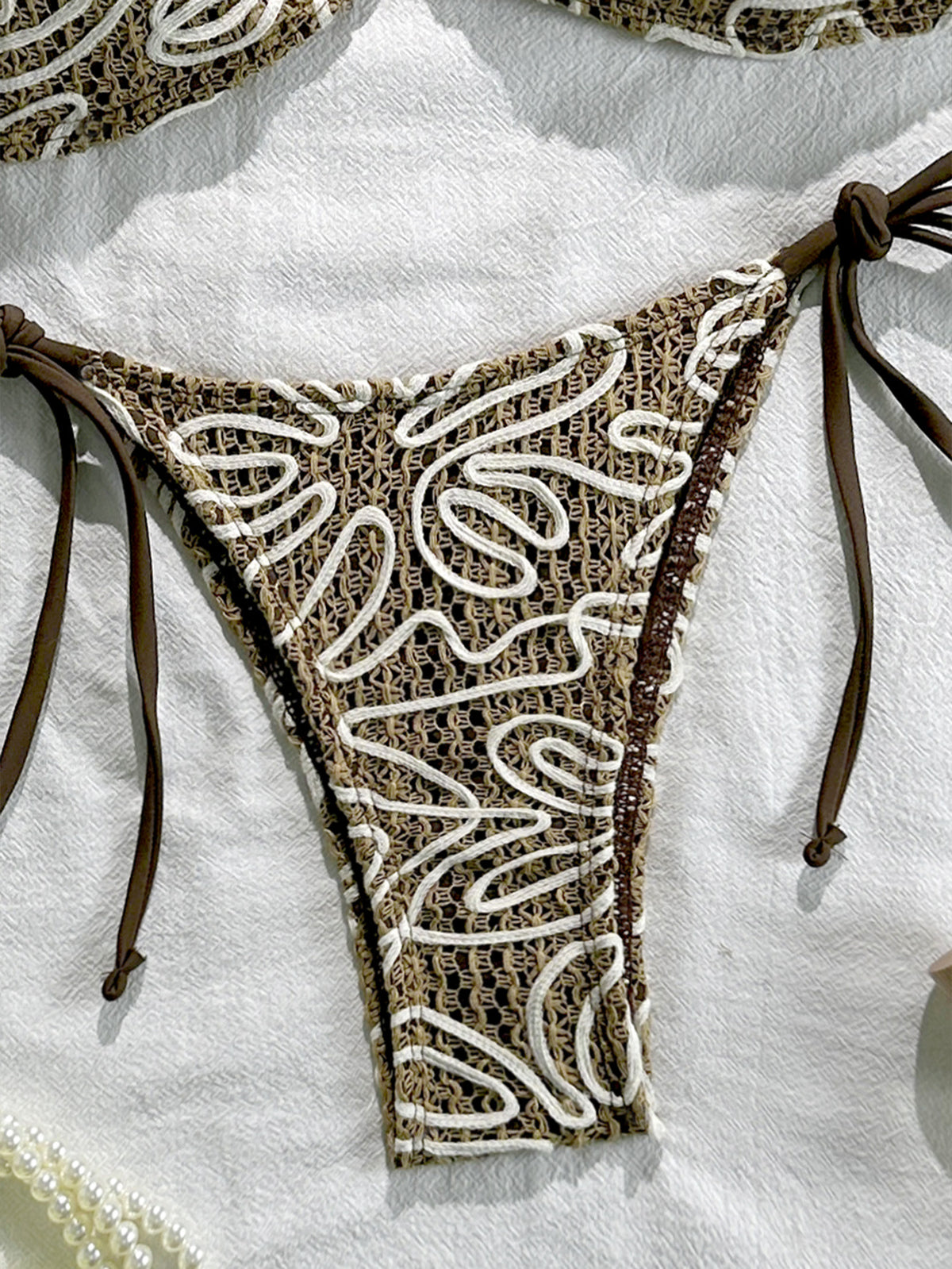 Side-tie bikini bottom with dark brown and white swirl lace pattern