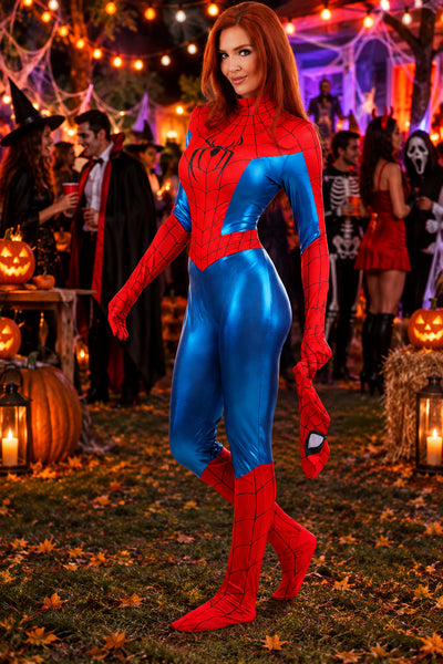 A woman wearing a shiny red and blue Spider-Man style bodysuit and matching boots stands outdoors at a Halloween party, with pumpkins, string lights, and other costumed people in the background.