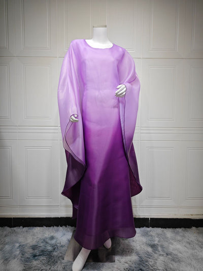 Ombre satin maxi dress with sheer batwing sleeves in lavender-to-purple, draped sides.