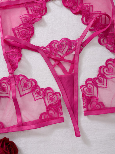 Close-up of rose red sheer mesh lingerie with heart embroidery and crisscross straps