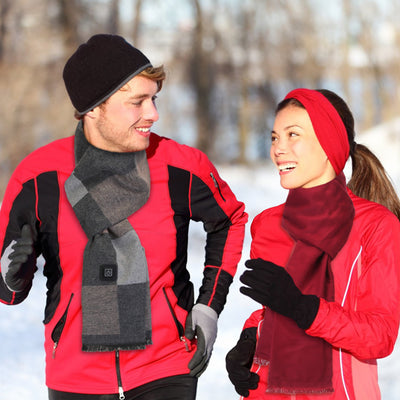 Two people in red jackets with scarves and gloves standing in a snowy landscape.