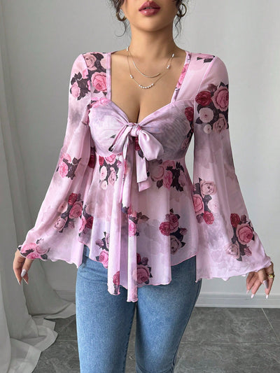 Soft pink floral blouse with bow front, bell sleeves, flared hem; close front view