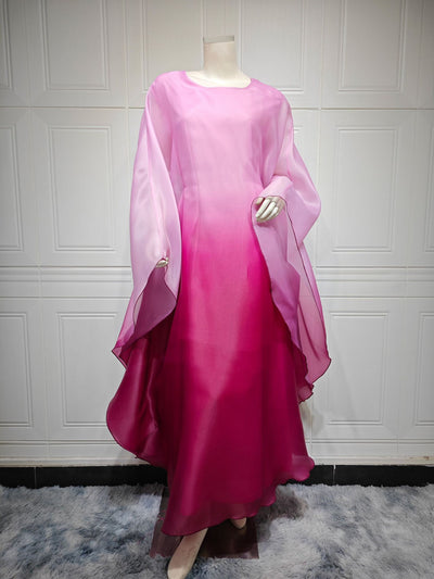 Ombre satin maxi dress with sheer draped batwing sleeves in pink-to-crimson.
