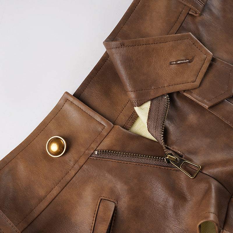 Front waist button and zipper detail with patch pockets on brown leather-look shorts.