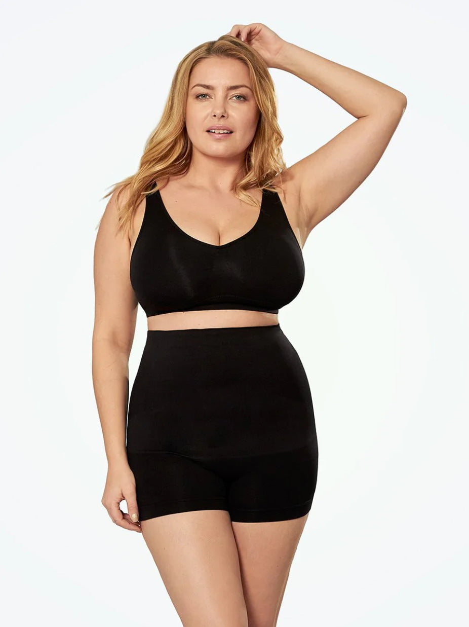 Woman wearing a black sports bra and high-waisted shorts on a white background
