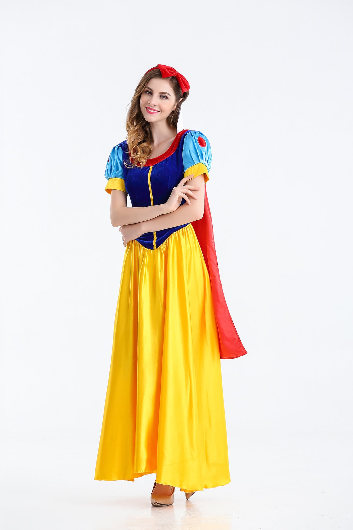 A woman modeling a Snow White costume against a plain white studio background. The costume includes a long yellow skirt, a blue bodice with yellow trim, blue puffed sleeves, a red cape, and a red headpiece.