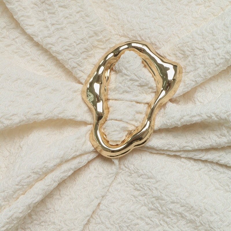 Gold oval metal accent with gathered stitching on cream knit dress.
