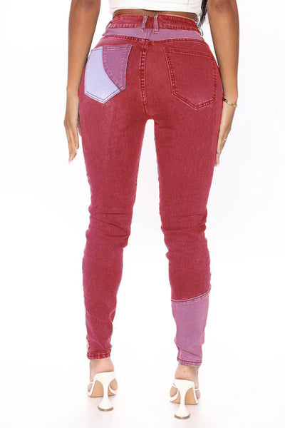 High-waist patchwork slim jeans in berry red with lavender geometric panels and contrast back pockets.