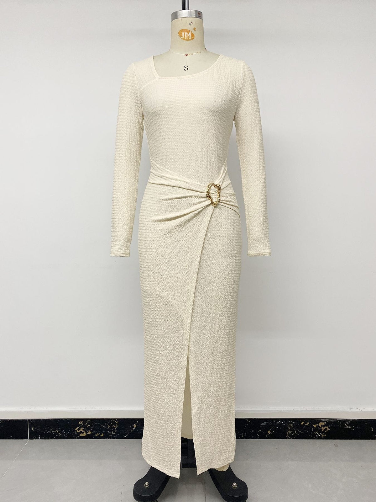 Cream knit maxi dress on mannequin with long sleeves, gathered hip and metal accent ring