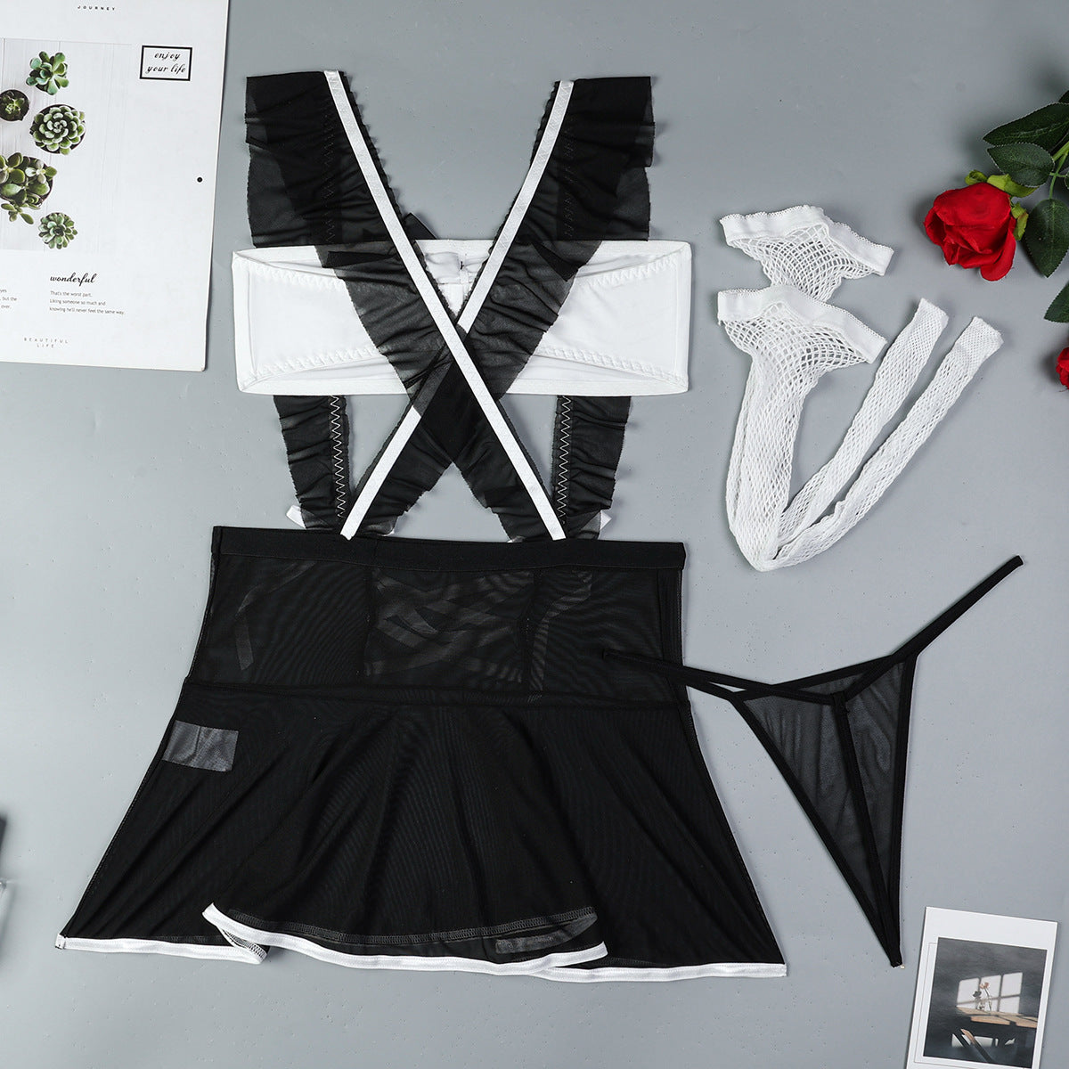 Black maid lingerie set laid flat with apron-style top, skirt, and matching stockings.