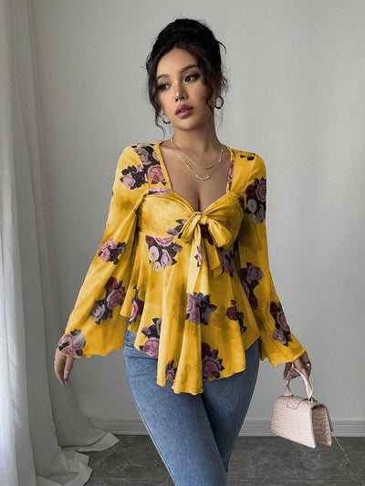 Mustard yellow floral blouse with bow front, bell sleeves, flared hem; front view