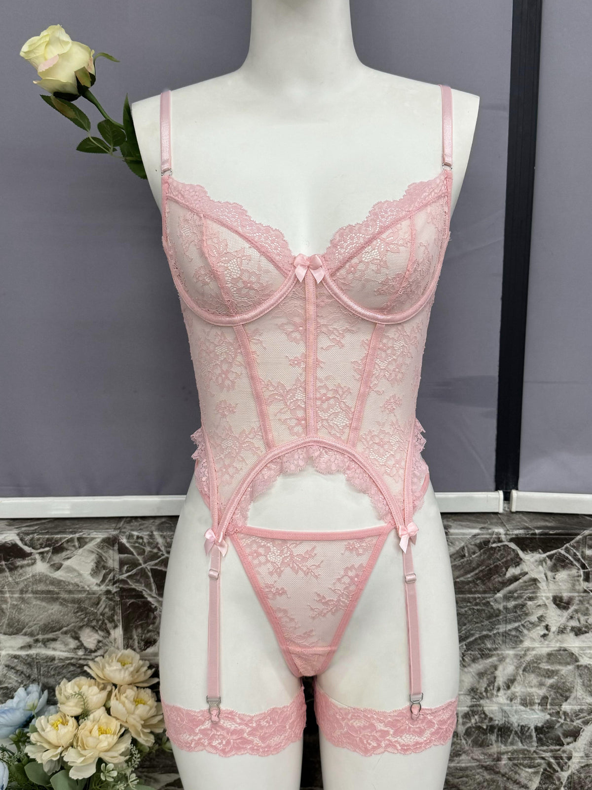 Pink lace bustier set with scalloped cups, underbust lace, and garter straps on mannequin