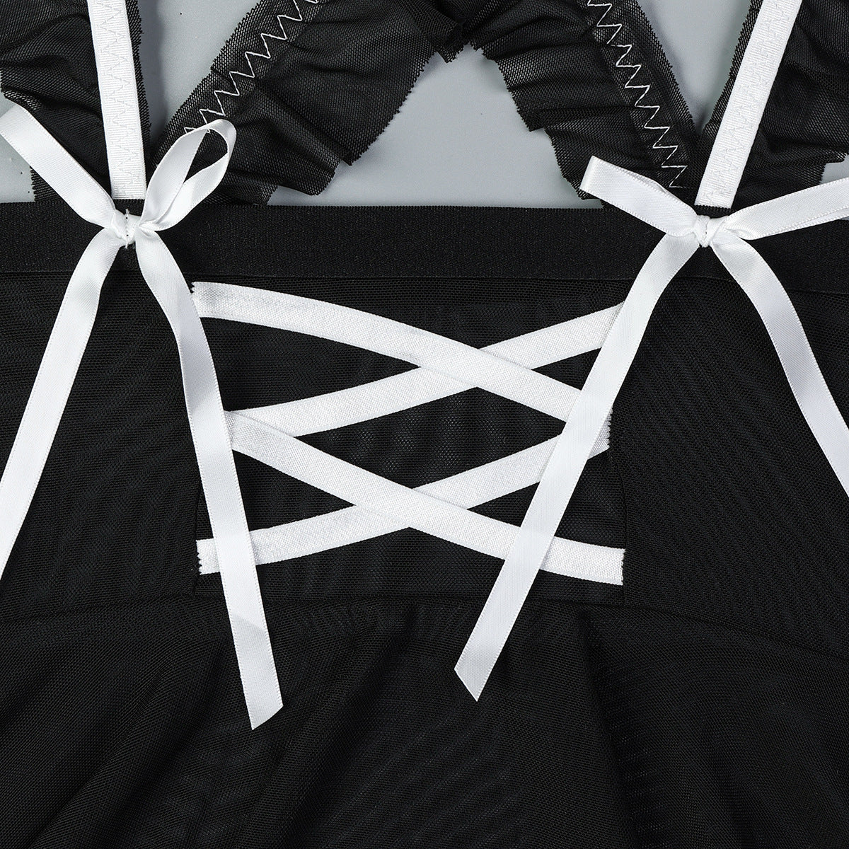 Black mesh corset-style lingerie with crisscross white ribbons and bow details.