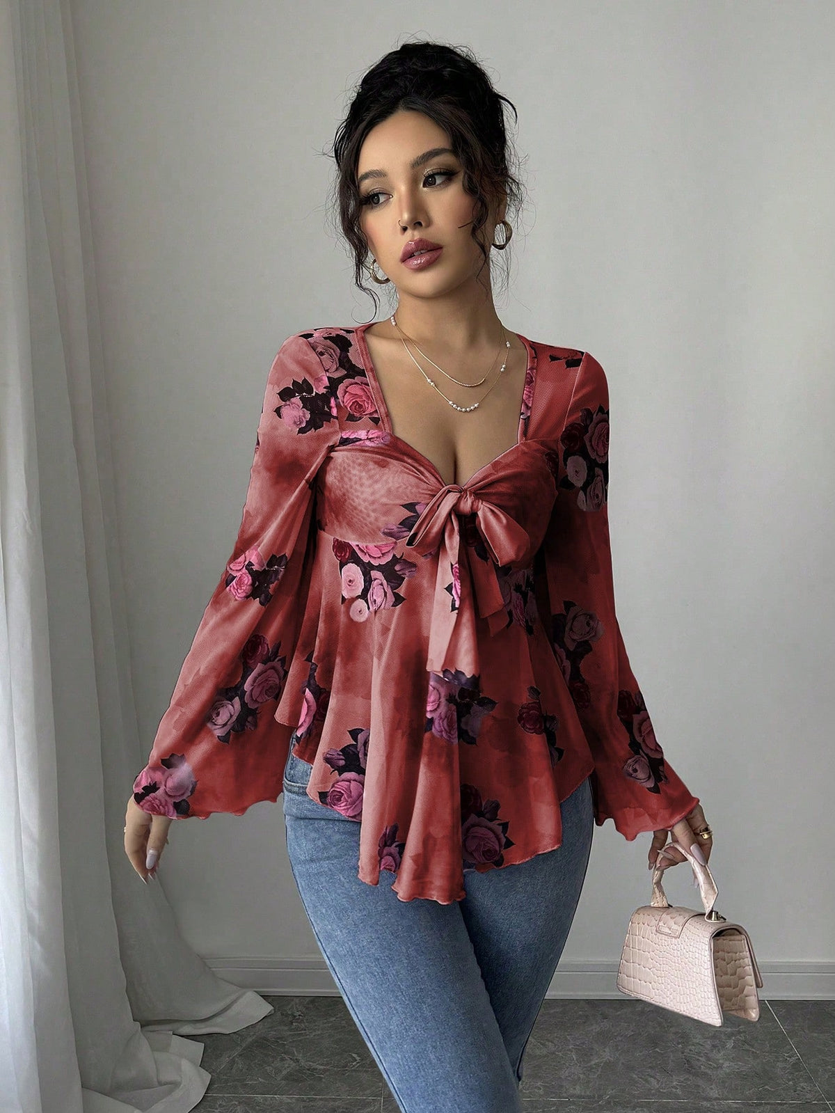 Front view Woman wearing a floral blouse and jeans, holding a handbag indoors.