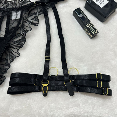 Black garter belt with thigh straps and gold buckles, shown with clasp hardware