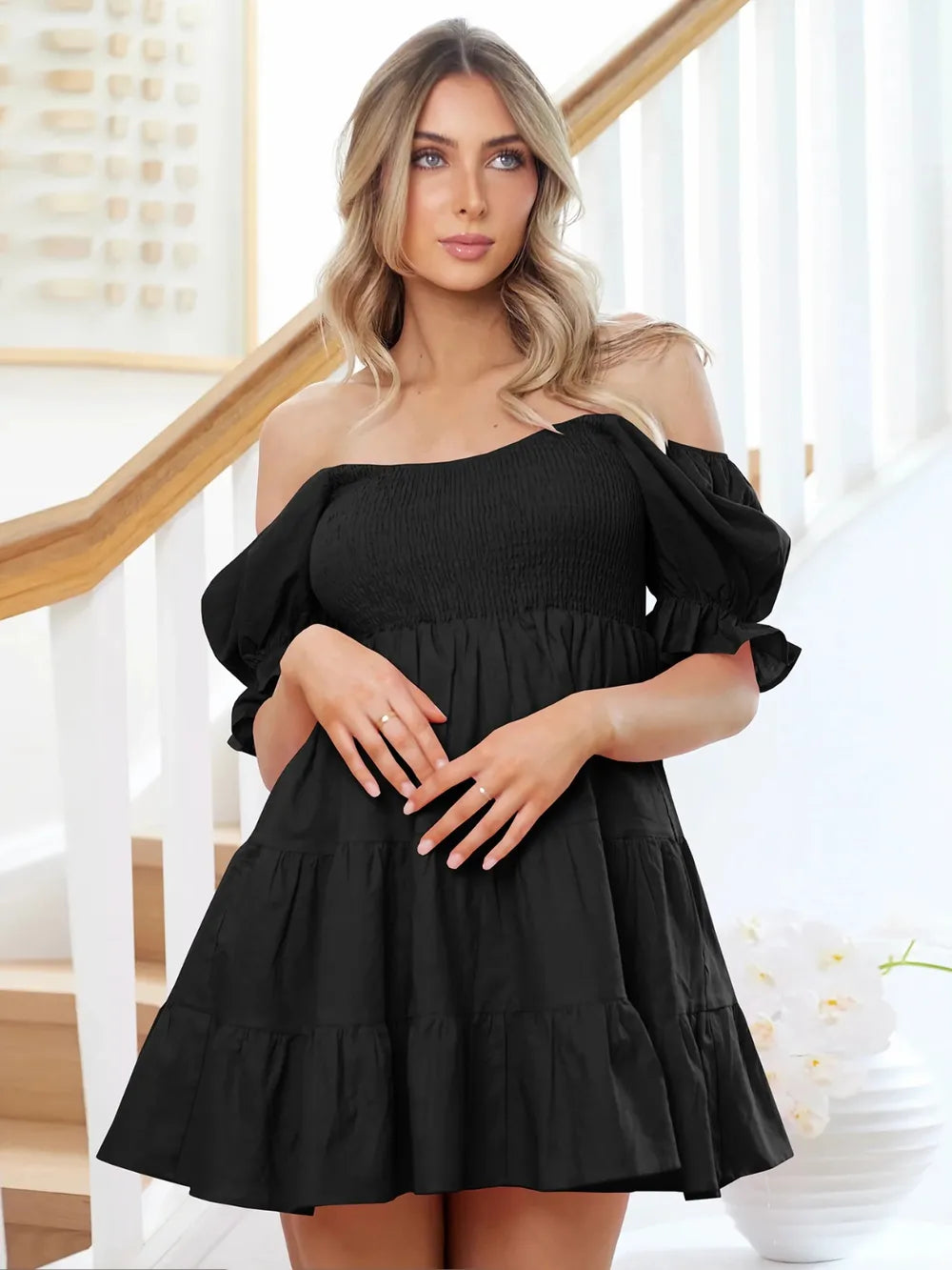 Black smocked tiered mini dress with off-shoulder neckline and puff sleeves