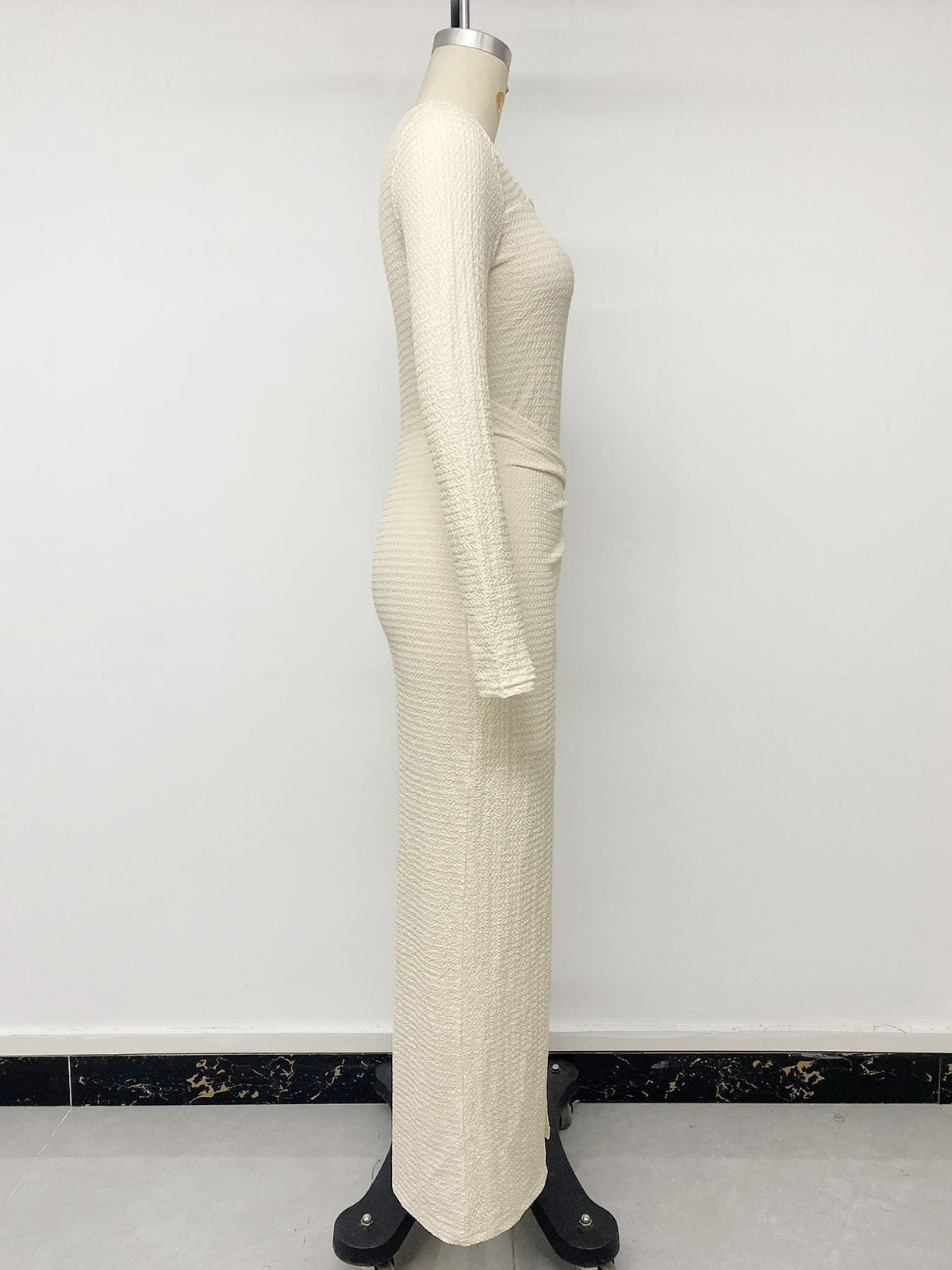 Cream knit maxi dress on mannequin, side view with long sleeve and gathered hip