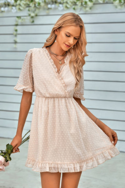 Model wearing a cream swiss dot ruffle midi dress with V wrap neckline, puff sleeves, elastic waist and ruffle hem