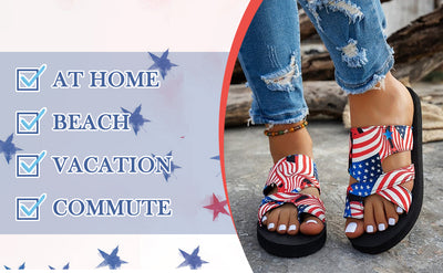 A person wearing red, white, and blue American flag print slide sandals with distressed blue jeans, standing outdoors on a stone surface. On the left is a graphic overlay with the text 'AT HOME', 'BEACH', 'VACATION', and 'COMMUTE' next to star icons.